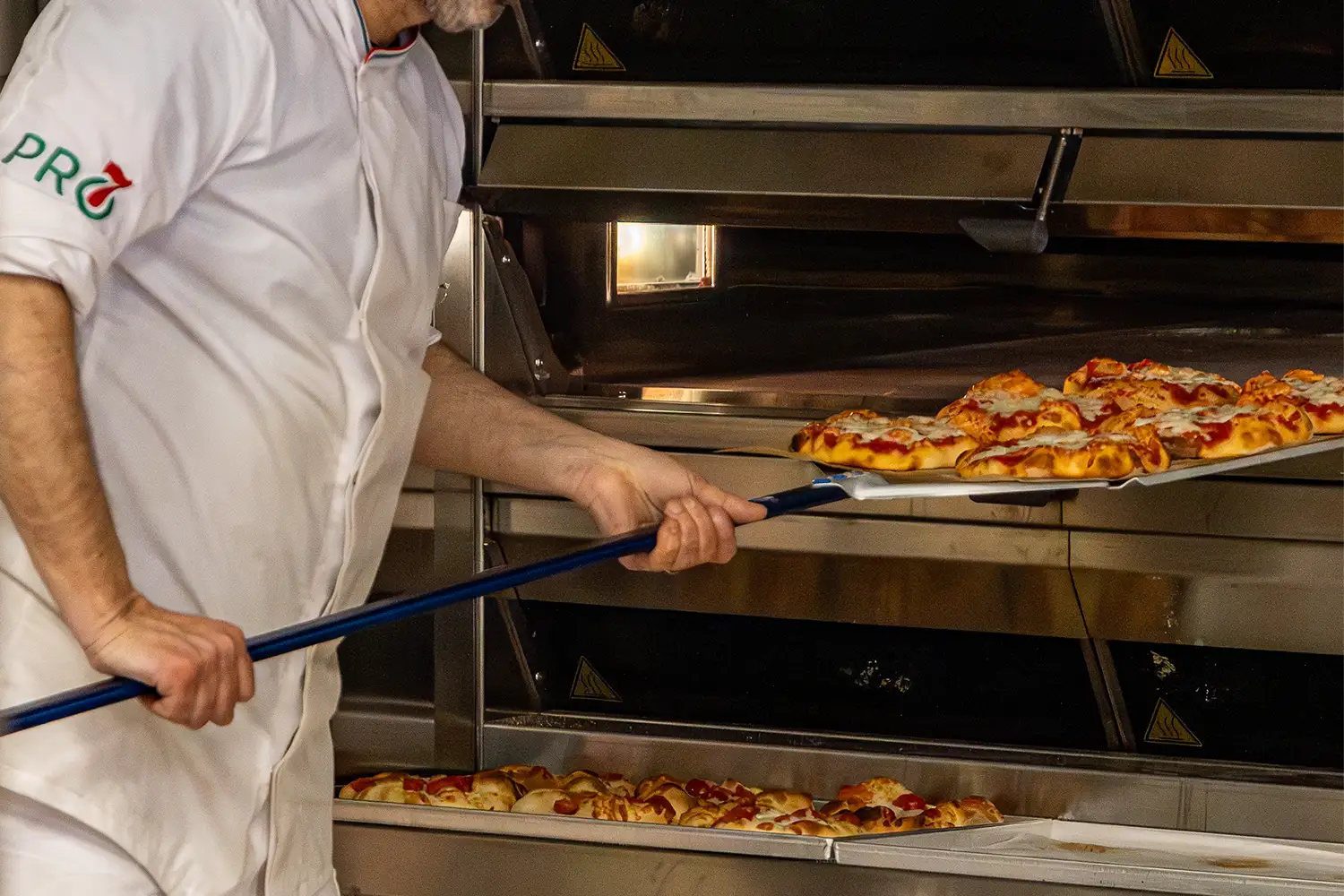 Pizzaiolo che inforna le pizze